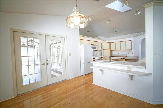 kitchen with white appliances, vaulted ceiling, pendant lighting, french doors, and sink