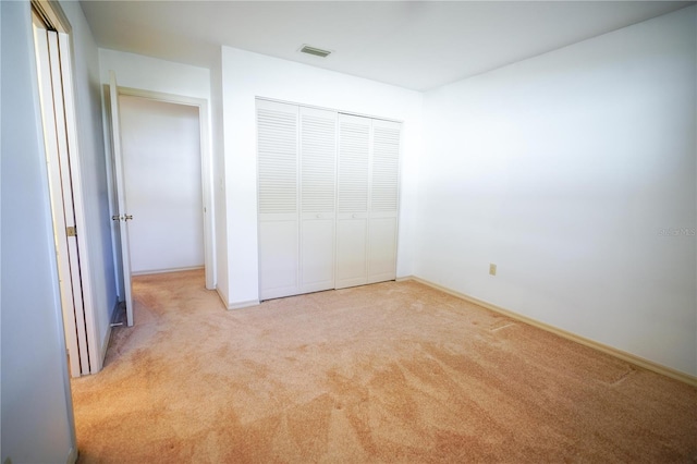 unfurnished bedroom with a closet and light carpet