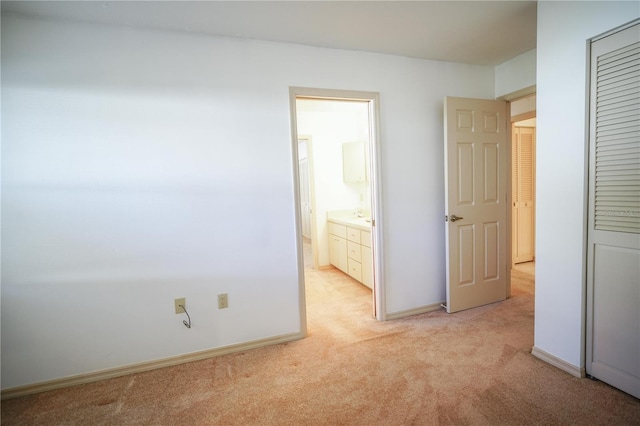 unfurnished bedroom featuring ensuite bathroom and light colored carpet