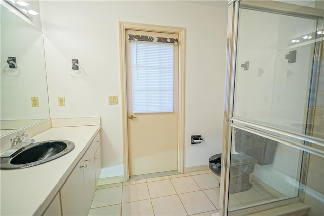 bathroom with a shower with door, tile patterned flooring, and vanity