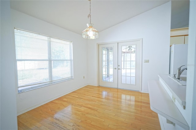 unfurnished dining area featuring light hardwood / wood-style floors, french doors, and vaulted ceiling