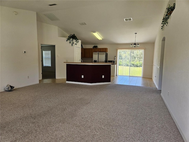 unfurnished living room featuring light colored carpet, a chandelier, baseboards, lofted ceiling, and visible vents