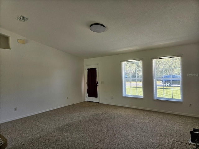 empty room with visible vents, baseboards, plenty of natural light, and carpet floors