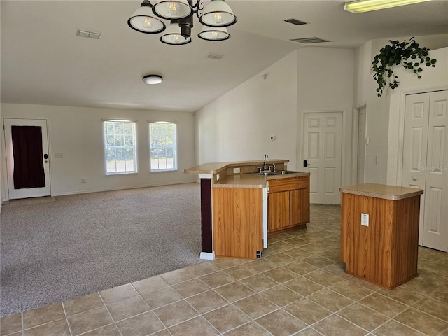 kitchen with a notable chandelier, sink, a kitchen island with sink, and light carpet