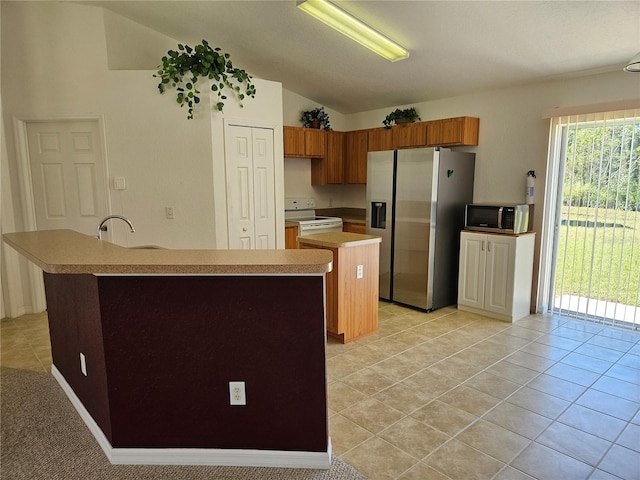 kitchen with a center island with sink, sink, vaulted ceiling, light tile patterned flooring, and stainless steel appliances