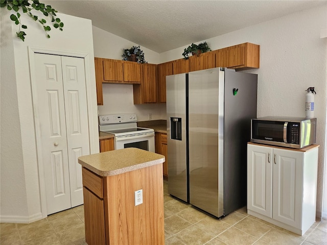 kitchen featuring a center island, a textured ceiling, brown cabinets, appliances with stainless steel finishes, and vaulted ceiling
