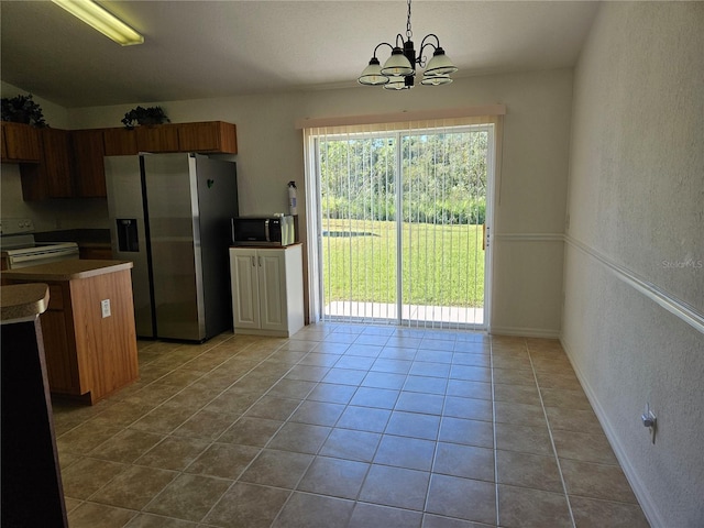 kitchen with stove, an inviting chandelier, hanging light fixtures, light tile patterned floors, and stainless steel fridge with ice dispenser