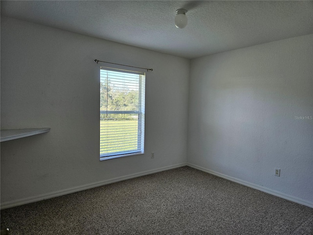 empty room with carpet flooring, a textured ceiling, and baseboards