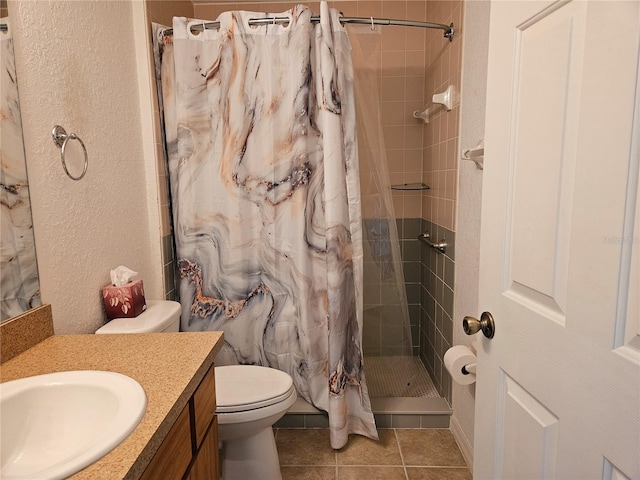 bathroom featuring a textured wall, tile patterned flooring, vanity, toilet, and a stall shower