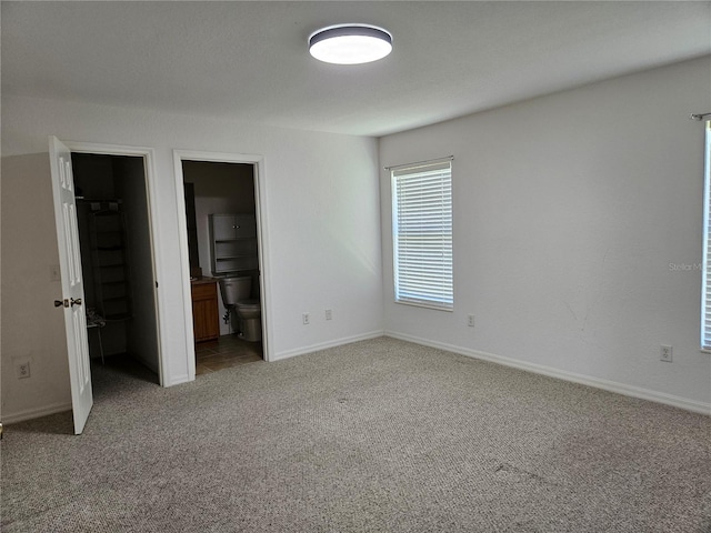 unfurnished bedroom featuring connected bathroom, carpet floors, and a spacious closet