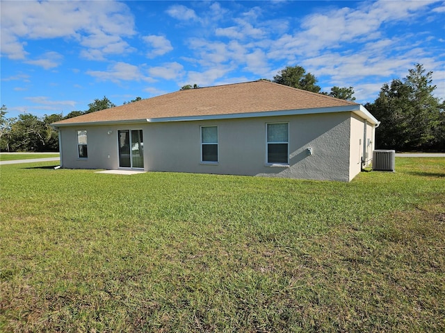 back of property with central AC and a yard