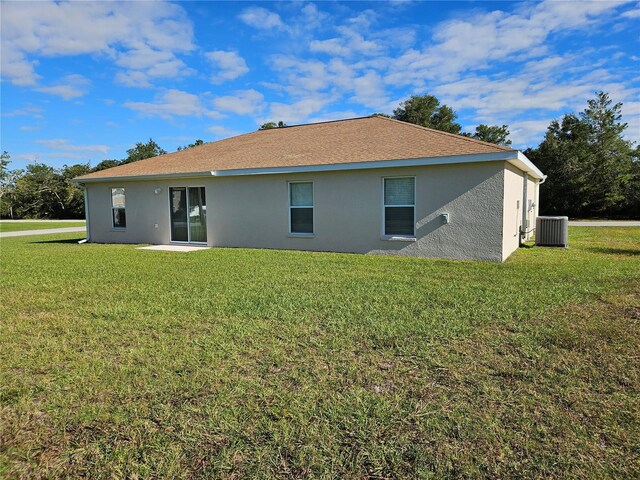 rear view of property with stucco siding, a yard, and cooling unit