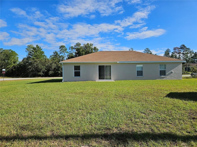 rear view of property with a lawn and stucco siding