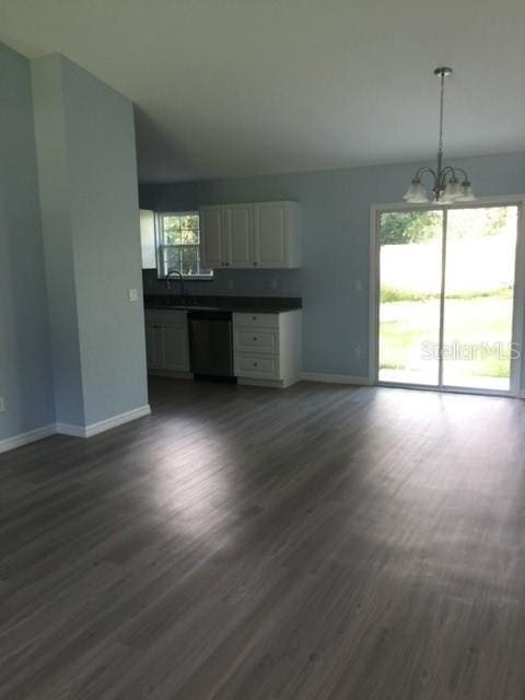 unfurnished living room featuring sink, a notable chandelier, and dark hardwood / wood-style floors