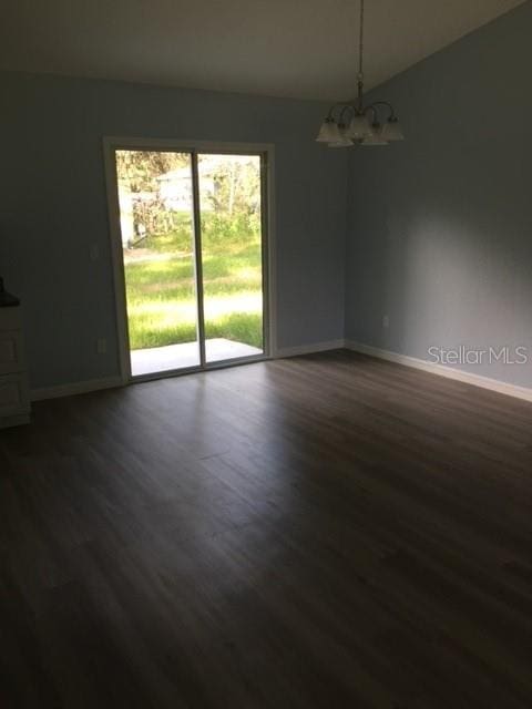 unfurnished room featuring a notable chandelier and dark hardwood / wood-style floors