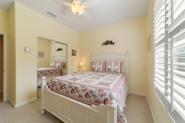 bedroom with ceiling fan, light colored carpet, and a closet