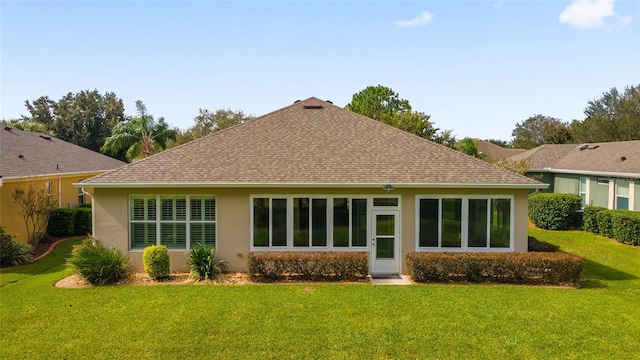 back of house with a lawn, roof with shingles, and stucco siding