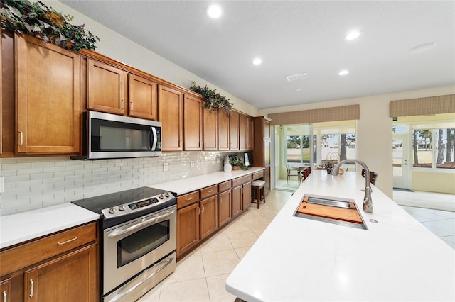 kitchen with appliances with stainless steel finishes, tasteful backsplash, light tile patterned floors, and sink