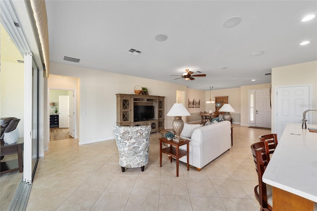 living room with ceiling fan, sink, and light tile patterned floors