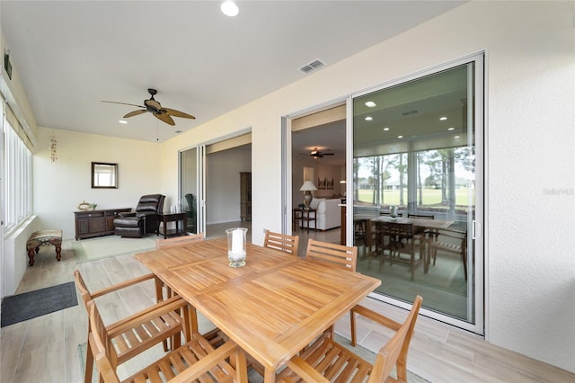 dining area with light wood-type flooring and ceiling fan