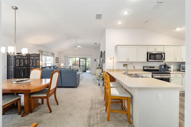 kitchen with stainless steel appliances, sink, ceiling fan with notable chandelier, hanging light fixtures, and white cabinets