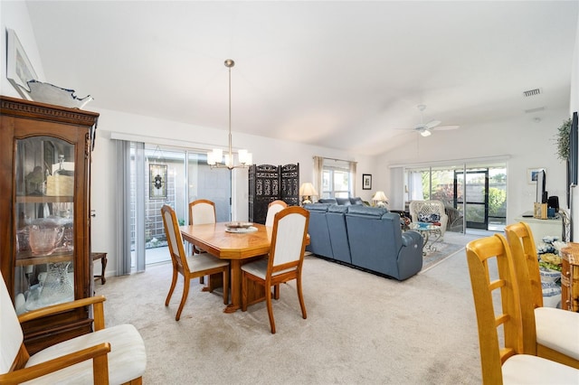 carpeted dining room with ceiling fan with notable chandelier and lofted ceiling