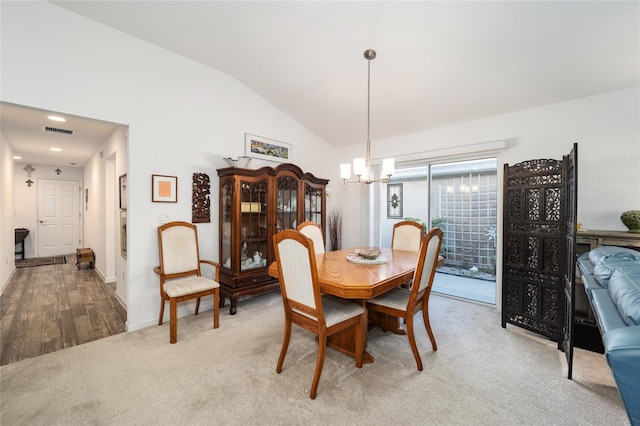 carpeted dining area featuring lofted ceiling and an inviting chandelier