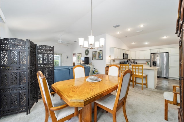 dining room with ceiling fan with notable chandelier, light hardwood / wood-style flooring, and lofted ceiling