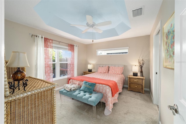 carpeted bedroom with ceiling fan and a raised ceiling