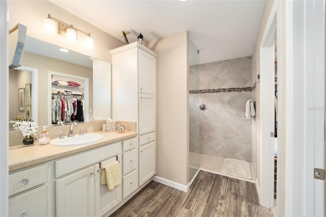 bathroom featuring hardwood / wood-style flooring, vanity, and a tile shower