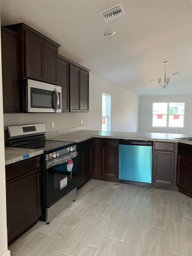 kitchen with dark brown cabinetry, vaulted ceiling, stainless steel appliances, and kitchen peninsula