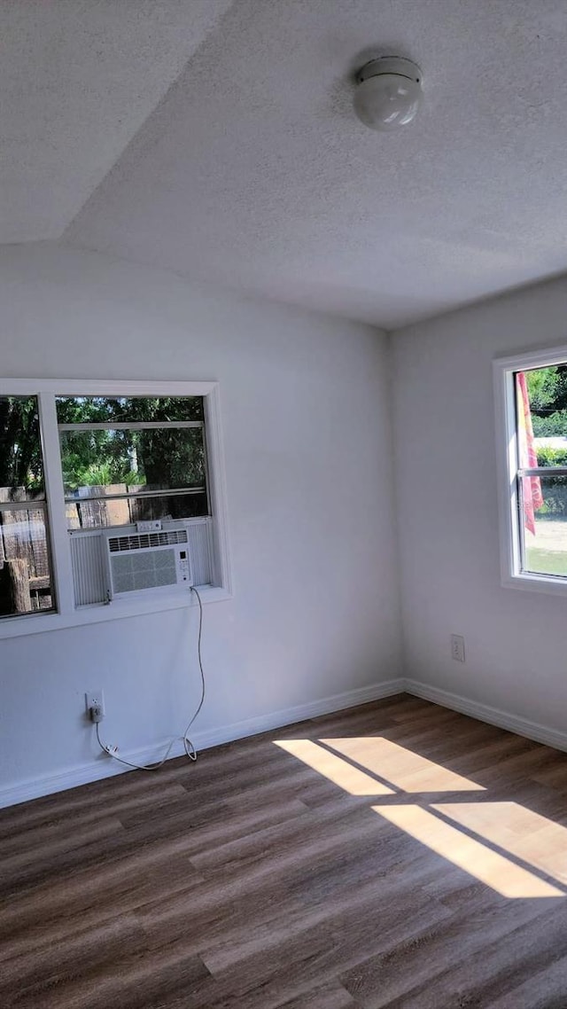 unfurnished room featuring vaulted ceiling, cooling unit, a textured ceiling, and dark hardwood / wood-style flooring