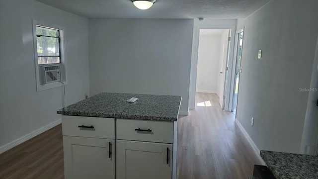 kitchen featuring stone counters, a center island, light hardwood / wood-style flooring, and white cabinets