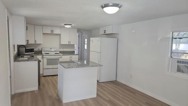 kitchen featuring white appliances, light hardwood / wood-style flooring, a kitchen island, and white cabinets