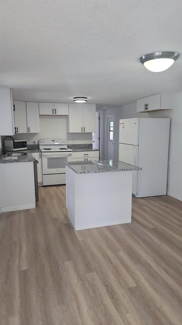 kitchen featuring a kitchen island, light hardwood / wood-style floors, white cabinetry, light stone counters, and white appliances