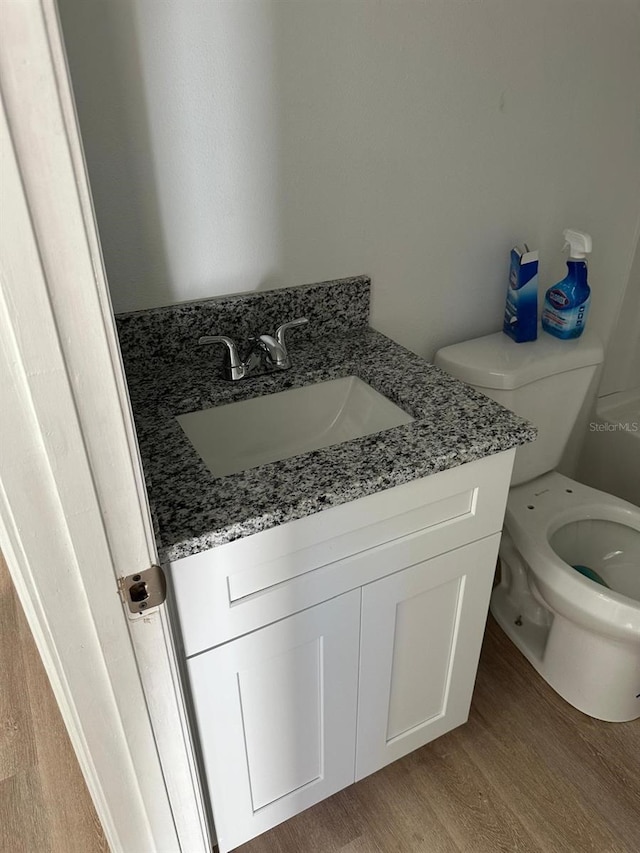 bathroom with toilet, hardwood / wood-style flooring, and vanity