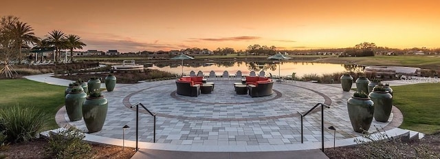 patio terrace at dusk with a yard and a water view