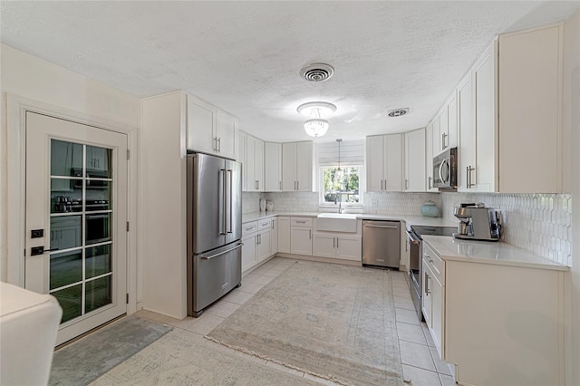 kitchen with light tile patterned floors, stainless steel appliances, sink, and white cabinets