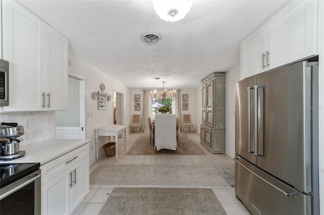 kitchen featuring appliances with stainless steel finishes, white cabinetry, decorative light fixtures, and a textured ceiling