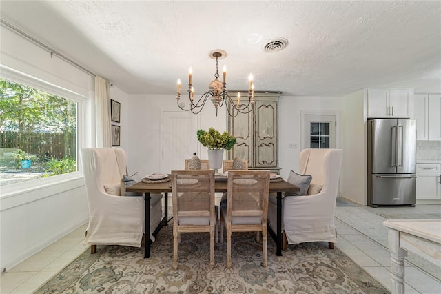 dining space featuring an inviting chandelier, a textured ceiling, and light tile patterned flooring