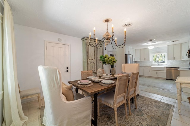 dining space featuring light tile patterned floors, a textured ceiling, sink, and an inviting chandelier