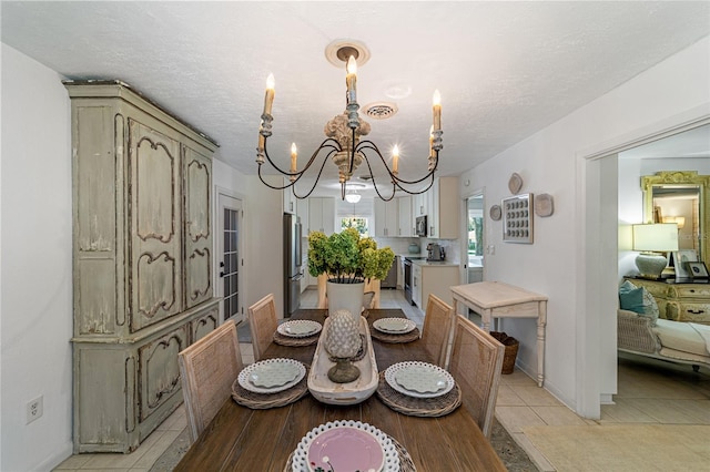 tiled dining space featuring a textured ceiling and a chandelier