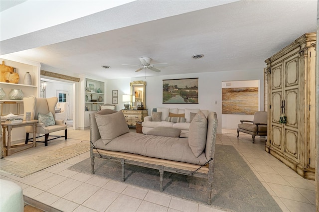 tiled living room with ceiling fan, built in features, and a textured ceiling