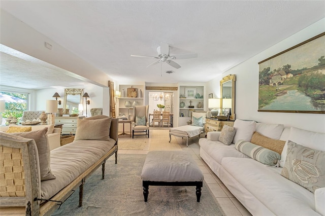 tiled living room with ceiling fan, built in features, and a textured ceiling