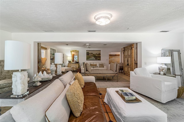 living room with ceiling fan and a textured ceiling