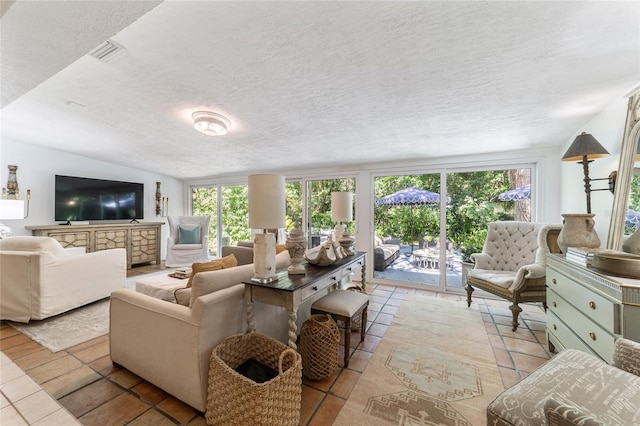 living room with lofted ceiling, light tile patterned flooring, and a textured ceiling