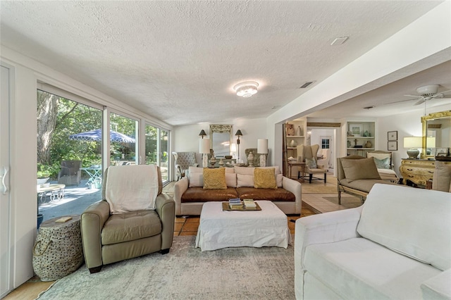 living room featuring light hardwood / wood-style flooring, a textured ceiling, and ceiling fan