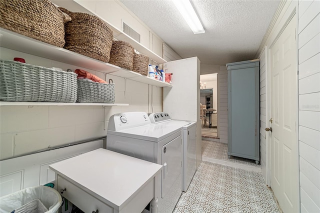 washroom with a textured ceiling and washer and clothes dryer