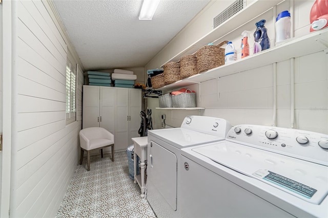 washroom with a textured ceiling and separate washer and dryer