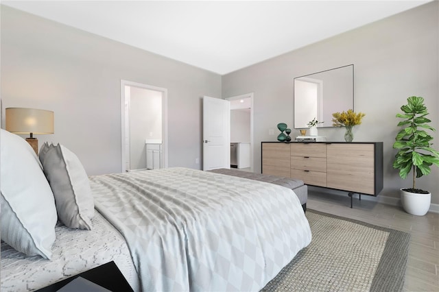 bedroom featuring connected bathroom and light hardwood / wood-style flooring